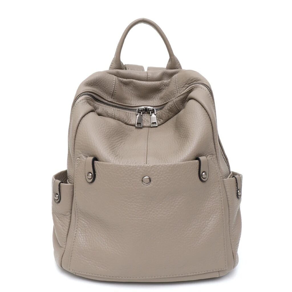 Ein taupefarbener Lederrucksack für Damen mit einer Reißverschlusstasche vorne, zwei Seitentaschen, einem Tragegriff oben und silbernen Beschlägen vor weißem Hintergrund.
